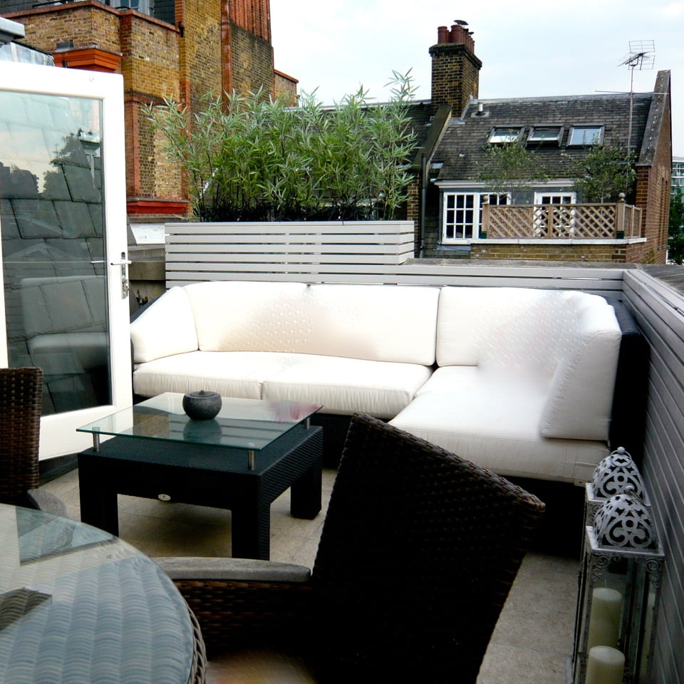 This bijoux penthouse terrace in London is simple understated but still stylish . The mirrors behind the grey timber strips catch the light to give it both day & nighttime interest together with inset lighting