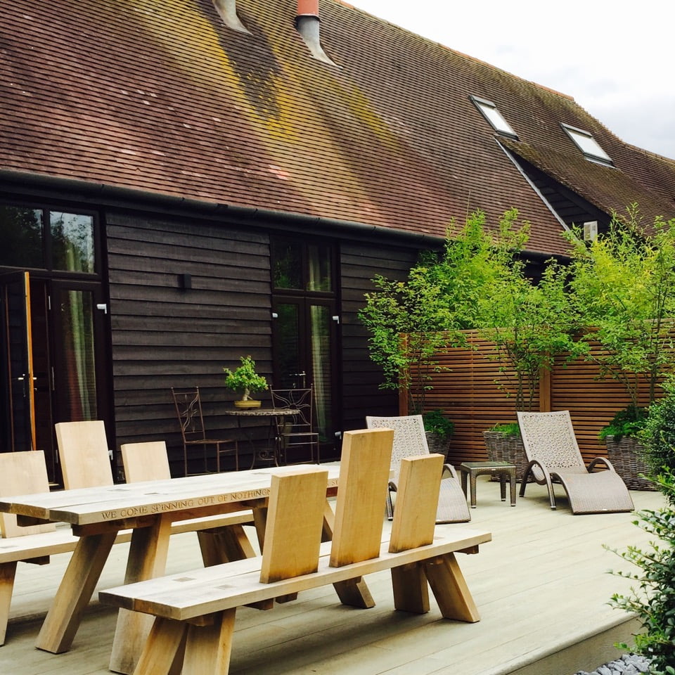 Baskets of Amelanchier trees & cedar strip fencing in this modern garden I designed for a barn conversion with furniture by Marnie at Green Oak furniture