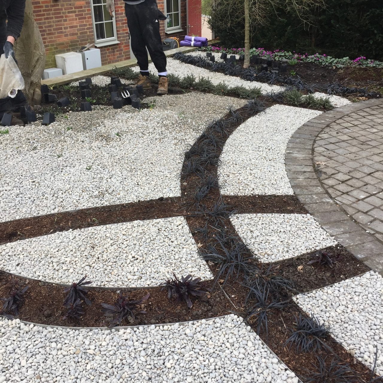 Laying gravel over the pretty ribbon planting for a small modern courtyard garden in Buckinghamshire