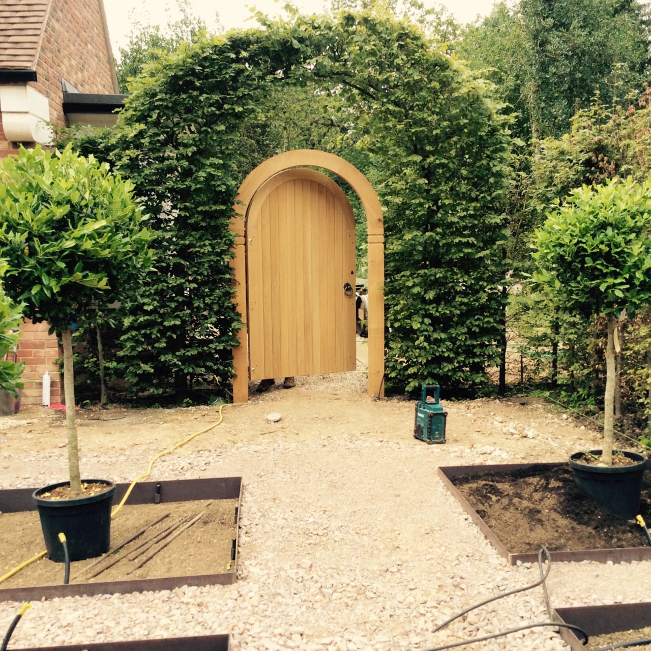 This is part of the parterre of a front garden near Finchampstead. There is a parterre of topiary & holly pompoms & the gate is bespoke