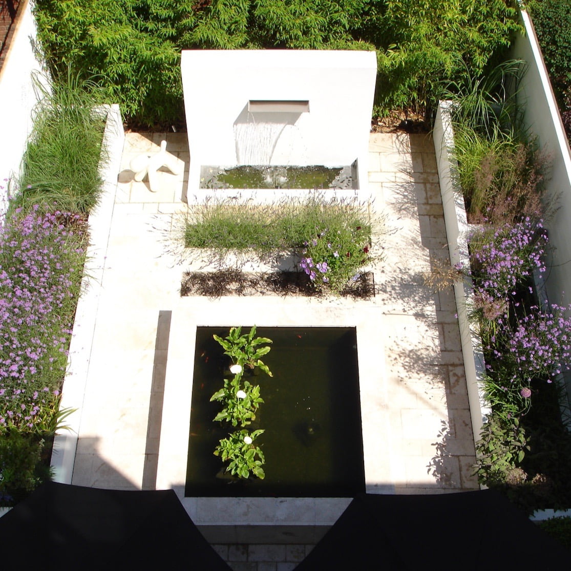 A simple contemporary courtyard garden in Henley on Thames by Jo Alderson Phillips featuring white rendered walls, a pool & water wall