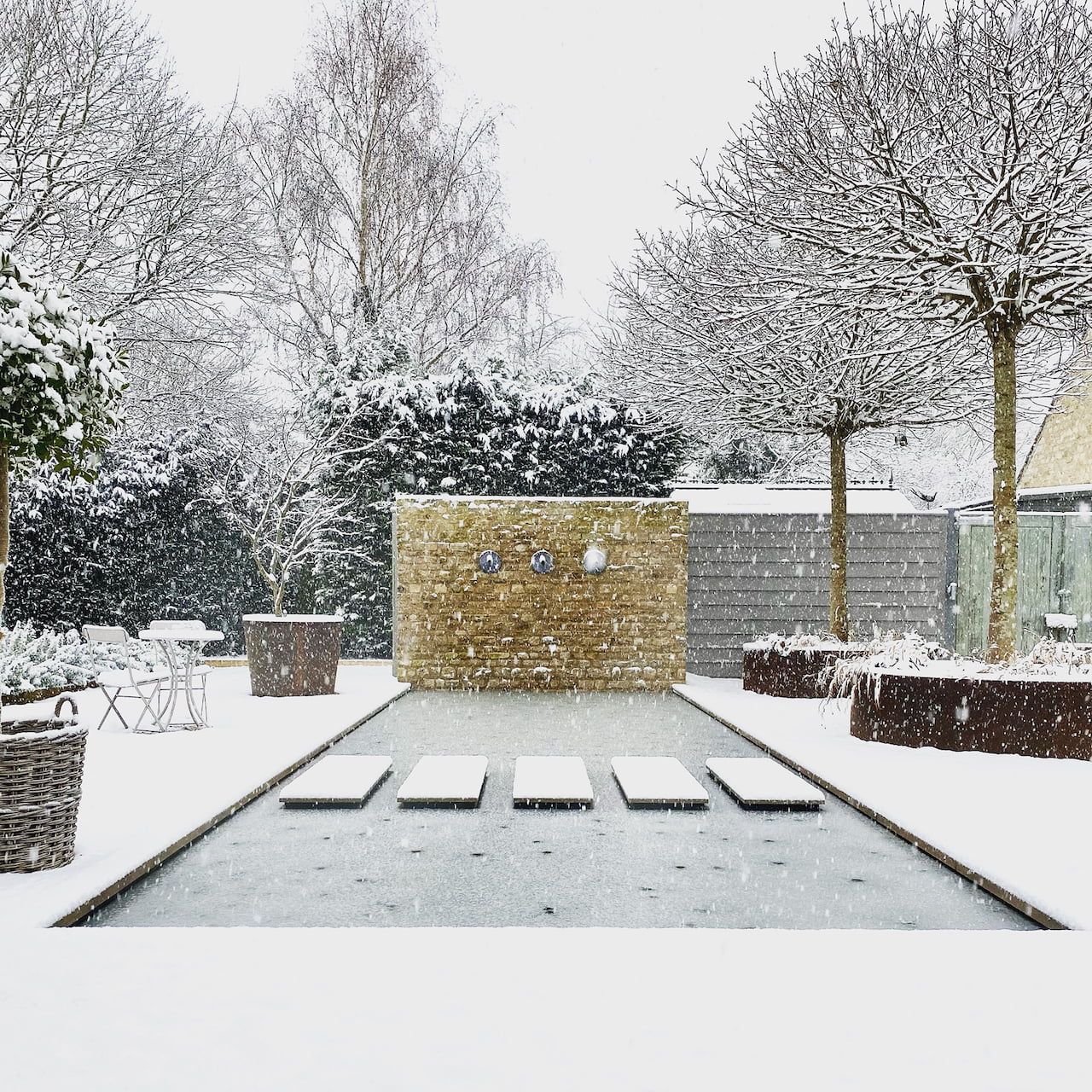 Our snowy courtyard by Jo Alderson Phillips. The Cotswold stone wall looks pretty against the white backdrop & the stepping stones really stand out in the pool